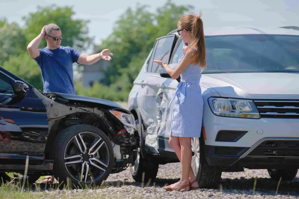 Two drivers discussing a car accident scene with visible damage on both vehicles, illustrating a common scenario for car accident claims in Fort Lauderdale.