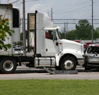 A collision between a large white truck and a severely damaged car at an intersection, illustrating the aftermath of a truck accident.