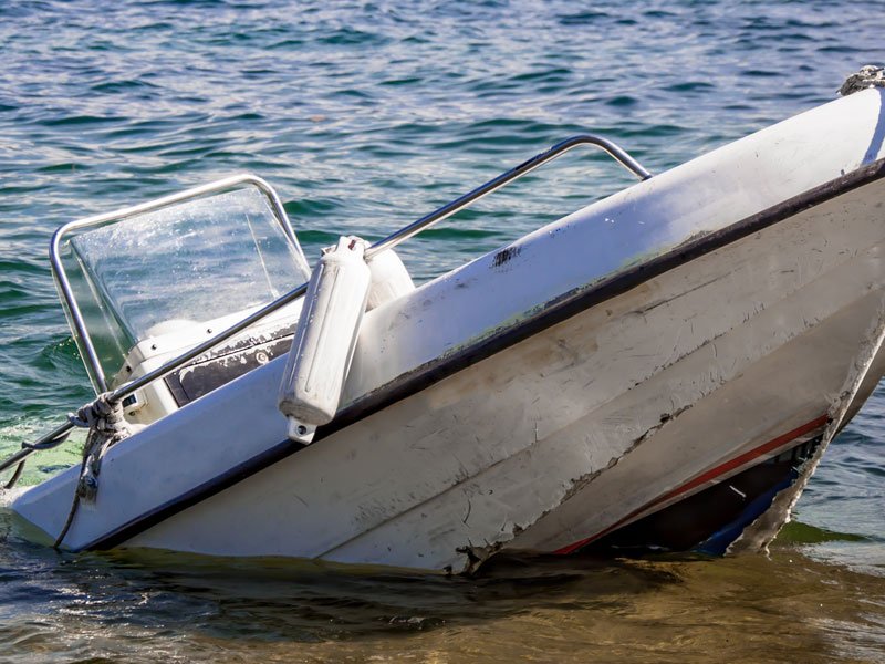 A partially submerged boat with visible damage, illustrating a boating accident scenario.